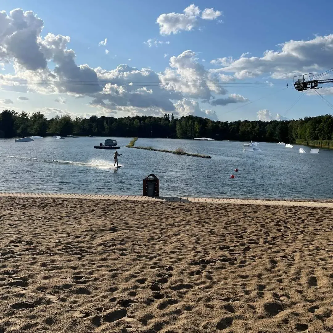 Sandstrand und Wakeboarder auf der Bahn im Wakepark Wake & Camp Ruhlsdorf